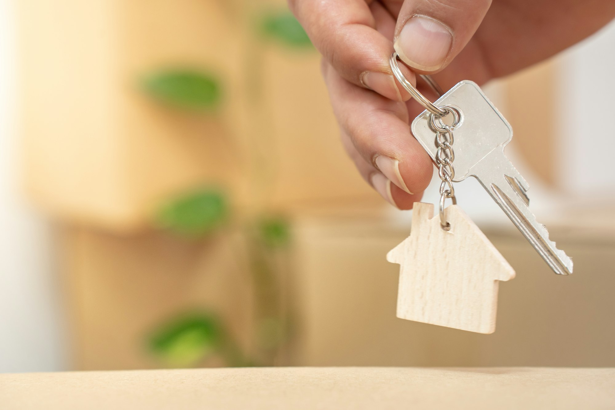 Hand holding new home keys on house shaped keychain real state moving relocation concept